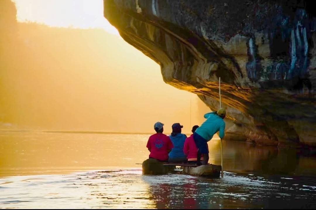 Pirogue passing beneath the Manambolo Gorge cliffs at sunset